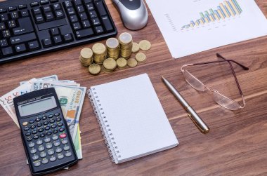 İş geçmişi, yukarıdan tahta bir masanın görüntüsü - boş defter ve kalem, dolar banknotları, grafik, gözlük, hesap makinesi, bilgisayar klavyesi ve fare