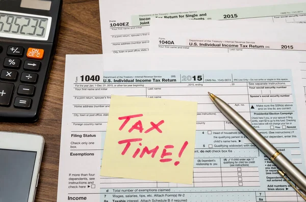 Tax time word on tax form with calculator, pen, glasses