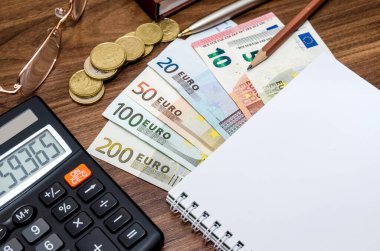 Boş defterli ofis araçları ve ahşap masadaki avro faturaları