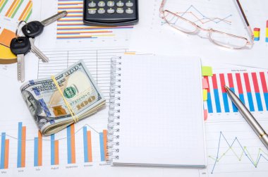 Para, anahtar, gözlük ve hesap makinesi olan diyagramların arkaplanındaki boş not defteri