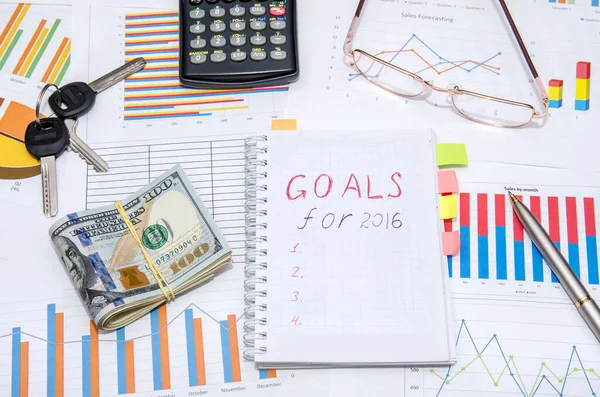 goals for 2016 written on notepad above diagrams with money, keys, glasses and calculator