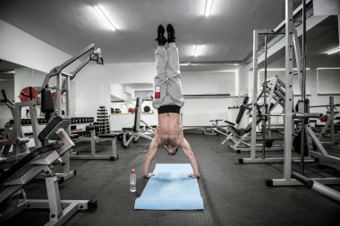 Sporcu adam spor salonunda farklı egzersizler yapıyor.