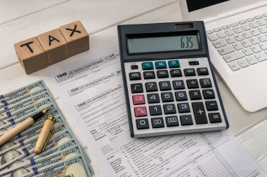 Dolar, dizüstü bilgisayar ve tahta küplü 1040 vergi formu