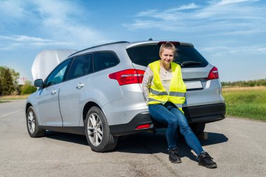 Güzel bir kadın kırık arabayı sırtından itiyor.