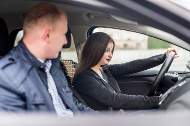 Eğitmeni olan genç bir kadın arabada oturuyor.