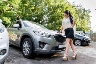 Arabanın yanında duran ve kameraya poz veren kadın.