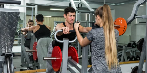 Coach training young and beautiful woman in gym