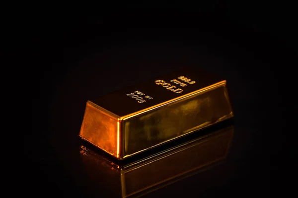 One gold bullion isolated on black .