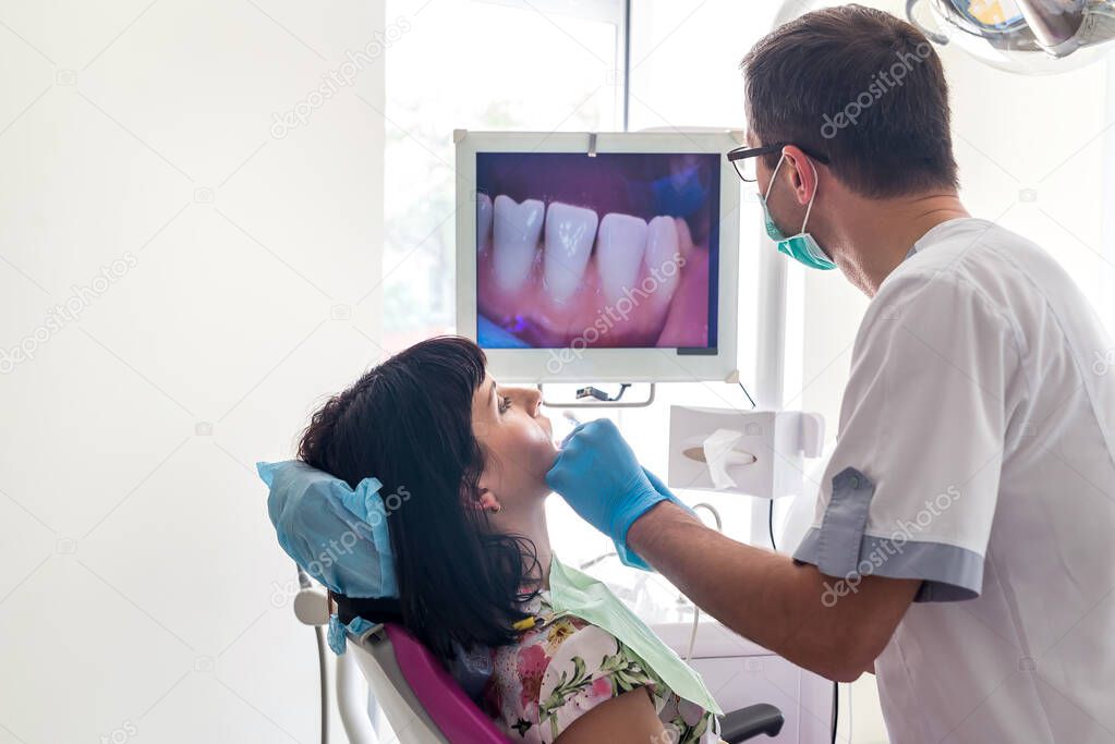 Dentist examining patient's teeth with intraoral camera