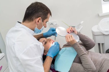 Doktor hasta diş sorunlarını aynada gösteriyor