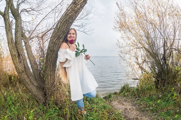 湖の水に対してポーズをバラを持つ女性 — ストック写真