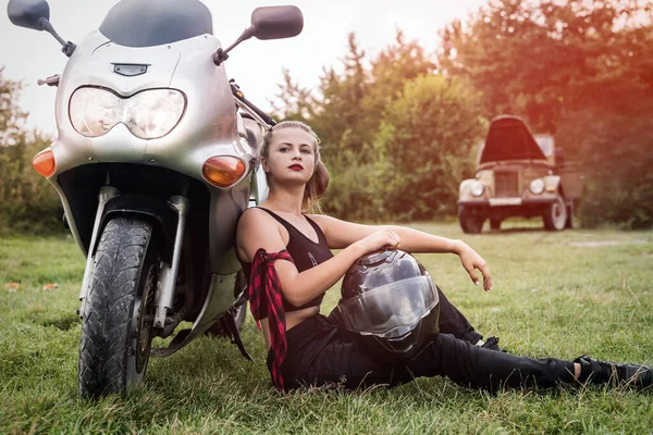 Beautiful woman posing with helmet and motorcycle