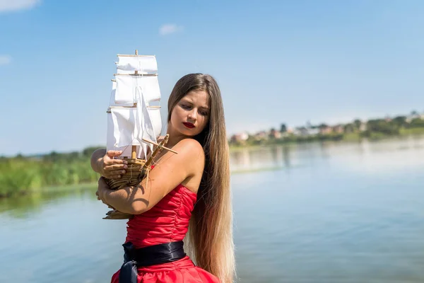 Jovem Mulher Vestido Vermelho Segurando Modelo Navio Costa — Fotografia de Stock