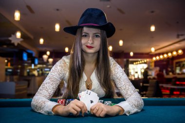 Şapkalı kadın kumarhanede dört as tutuyor.