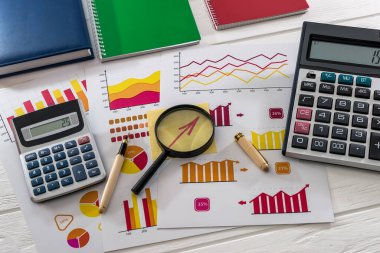 Büyüteç, kalem ve hesap makineli iş grafiklerinin üst görünümü