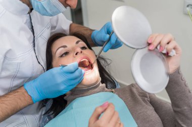 Doktor hasta diş sorunlarını aynada gösteriyor