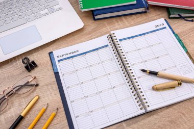 Tahta masada dizüstü bilgisayarla açılmış bir not defteri.