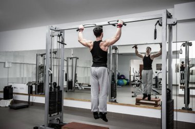 Adam jimnastik salonunda bazı egzersizler yapıyor.