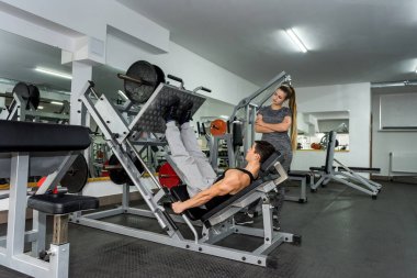 Spor salonunda ağırlık kaldırmada yardımcı antrenör.