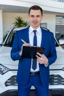 Danışman arabaların arka planında belgeler tutuyor.