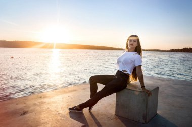 Göl kıyısında poz veren kadın Küp 'te oturuyor.