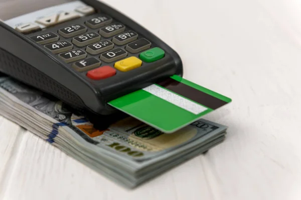 Banking terminal with green credit card and dollar background