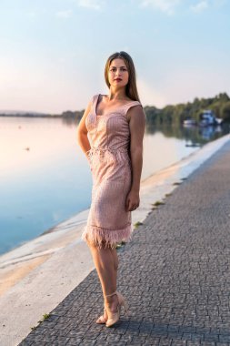 Gün batımında kumsalda zarif elbiseli güzel bir kadın.