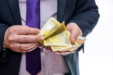 Takım elbiseli adam Euro banknotlarını sayıyor.