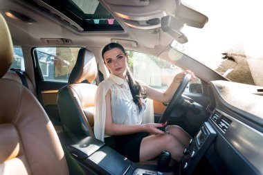 Arabanın içinde direksiyon tutan güzel bir kadın.
