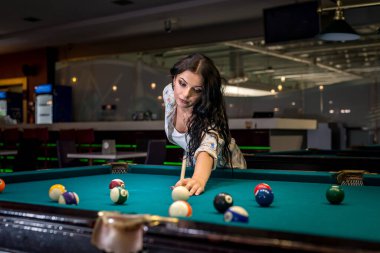 Kadın bardaki bilardo maçına odaklanmış.