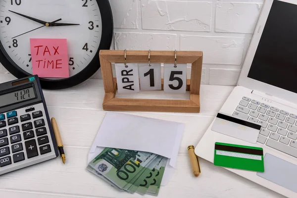 Tax time with clock, laptop and euro banknotes