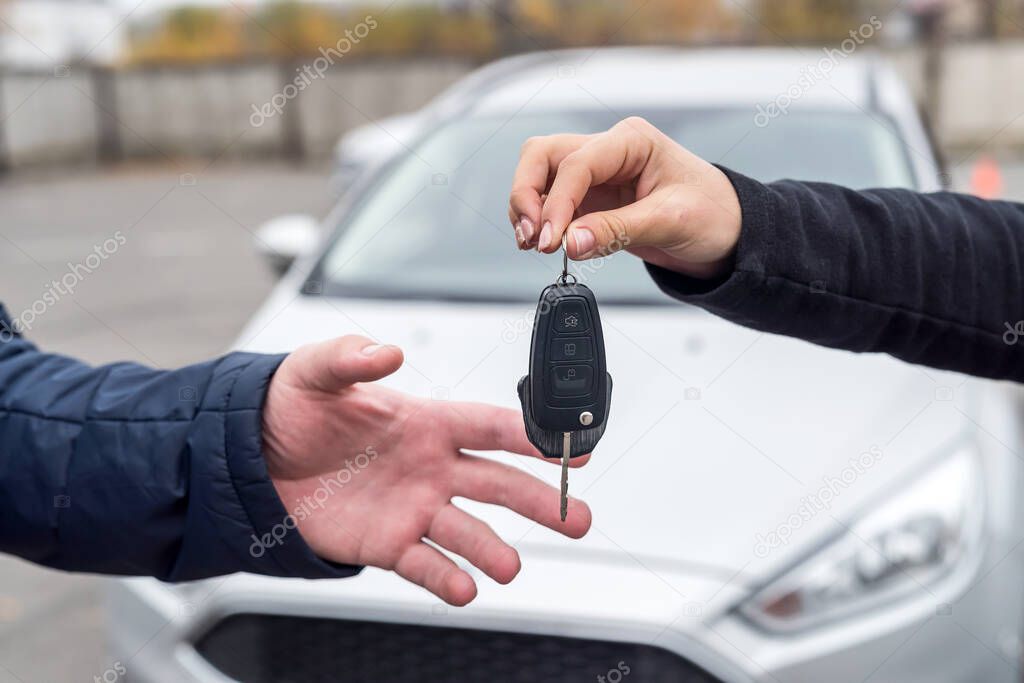 Hands with keys against new car close up