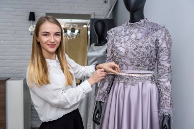 Düğün salonunda mankenle poz veren genç bir tasarımcı.