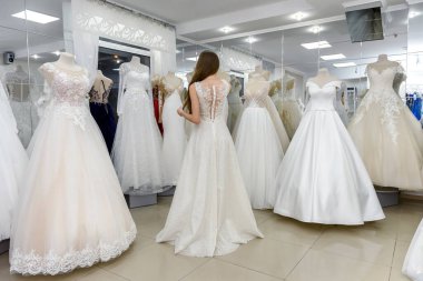 Gelinlik giymiş zarif bir bayan düğün salonunda duruyor.