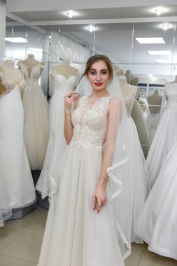 Genç ve güzel bir gelin kuaförde elbise ve peçe seçiyor.