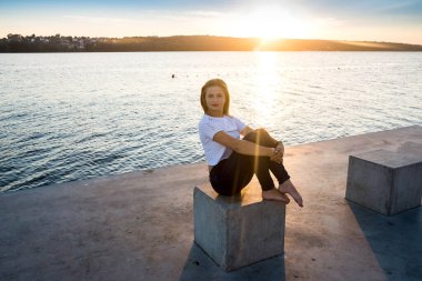 Göl kıyısında poz veren kadın Küp 'te oturuyor.