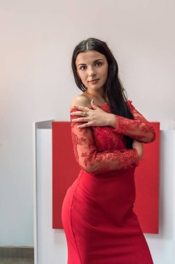 Uzun kırmızı elbiseli, koyu saçlı, genç ve seksi bir manken.