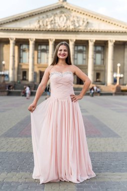 Pembe elbiseli genç, ince, güzel bir mankenin şehir portresi.