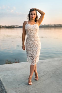 Gün batımında kumsalda zarif elbiseli güzel bir kadın.