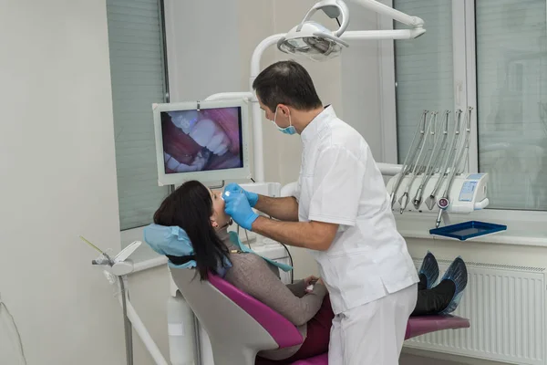 Dentist checking woman\'s teeth with mirror during visit