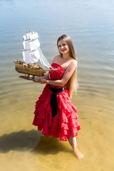 Young Woman Red Dress Holding Ship Model Seashore — Stock Photo, Image