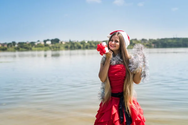 ギフトボックスとクリスマスガーランドと赤いドレスの美しい女性 — ストック写真