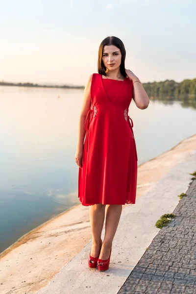 海岸の赤いドレスを着たブルネットの女性 — ストック写真