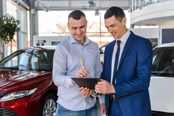 Man in showroom signing contract about car purchase