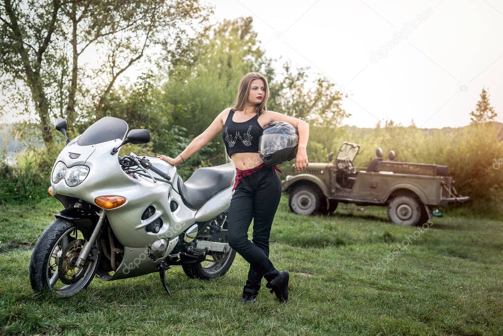 Woman with helmet in her hand, stand near motorcycle