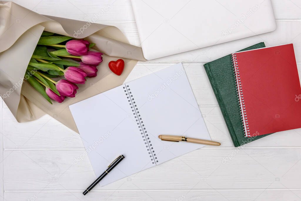 Bouquet of tulips and blank notepad on wooden table