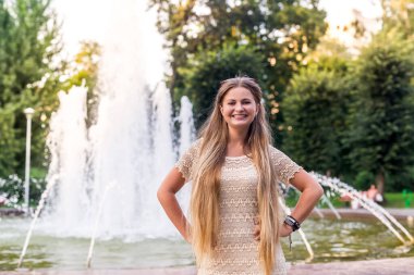 Şehirde fıskiyelerin yanında poz veren güzel bir kız.