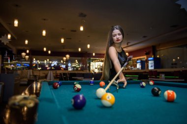 Young and beautiful woman in pub playing billiard