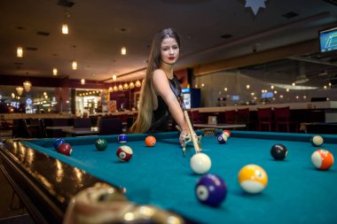 Young and beautiful woman in pub playing billiard