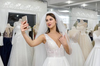 Genç gelin kuaförde gelinlik içinde selfie çekiyor.